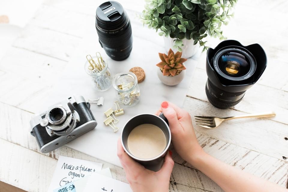 Máy ảnh, ống kính và tách cà phê trên bàn sáng